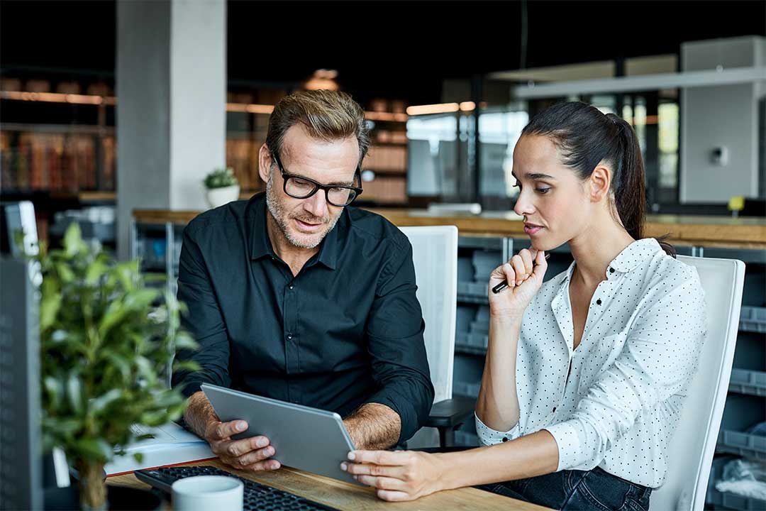 Man and woman reviewing benefit costs on tablet.